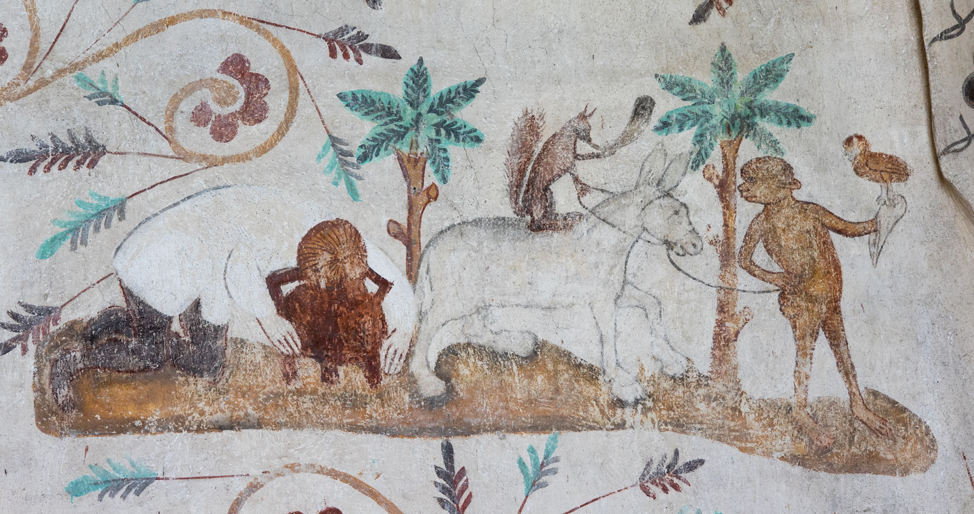 Man med huvudet i en gryta, apliknande figur med en falk på handen leder en åsna, riden av en hornblåsande ekorre - Tensta kyrka