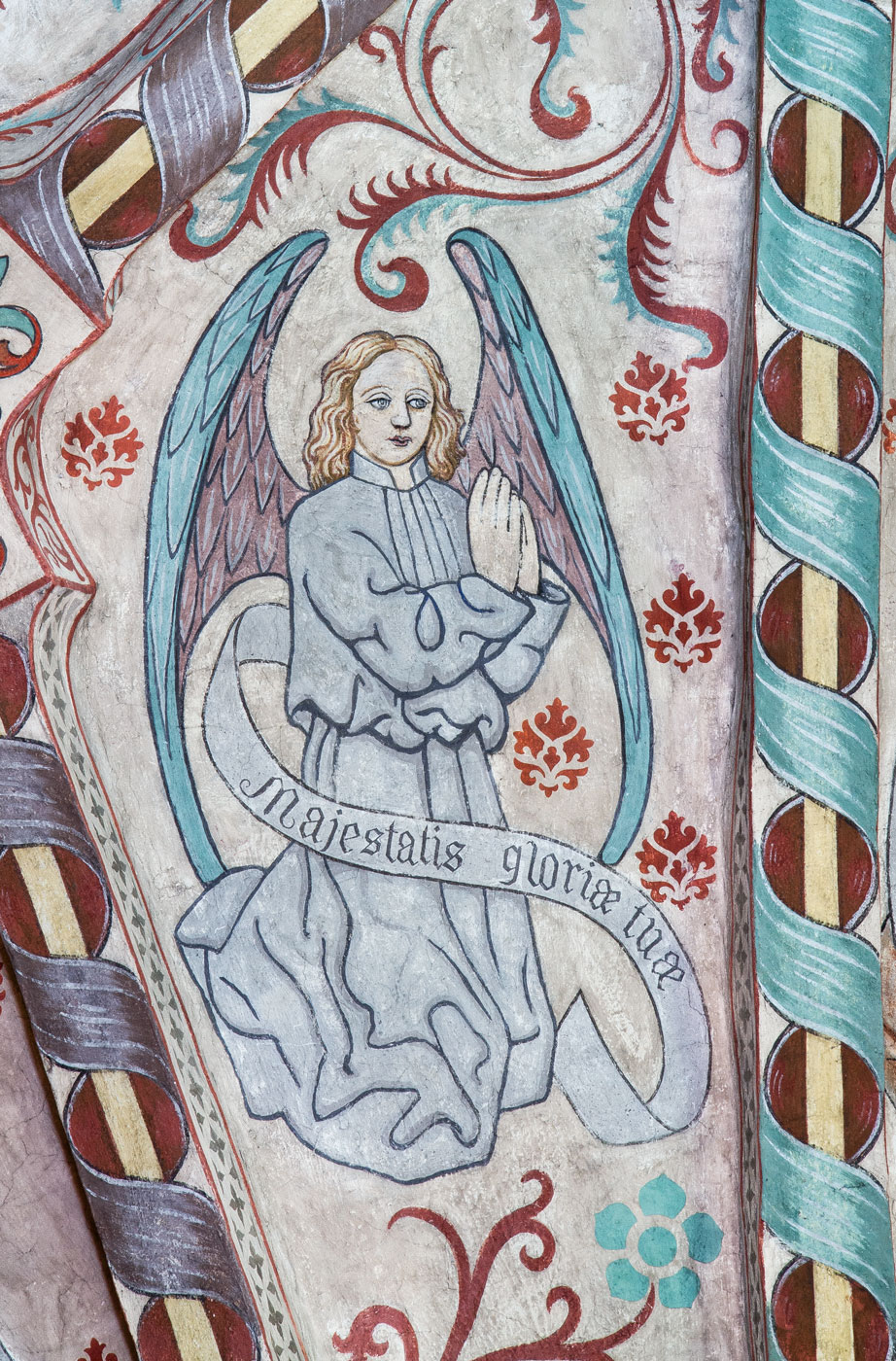 En av åtta änglar med hymnen Te Deum uppdelad på åtta språkband: Majestatis gloriae tuae (Ö) - Vittinge kyrka